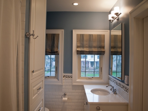 Custom roman shades and blue painted walls add depth to the mostly white master bathroom.