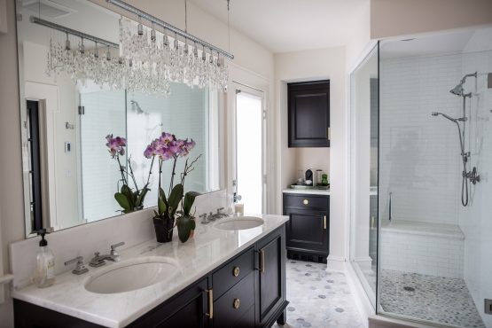 The oversized, walk-in shower boasts a custom bench, floor to ceiling glass panels and updated classic features, such as the white 2x8 subway tile and 1" hexagon floor. A linen cabinet and coffee bar combo is tucked in the corner of the bathroom, allowing for convenience, as well as extra storage space.